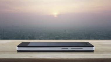 Hediye kutusu mutlu yeni yıl 2024 düz simgesi modern akıllı cep telefonu ekranında ahşap masa üzerinde ve günbatımında gökdelen, klasik tarzda, iş yeni yılı 2024 mağaza online konsept