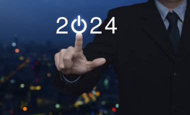 2024 'e basan iş adamı, bulanık renkli gece aydınlığı, modern şehir kulesi ve gökdelen üzerine iş hayatına yeni bir imajla başlıyor. Yeni yıl 2024 başarı kavramı.