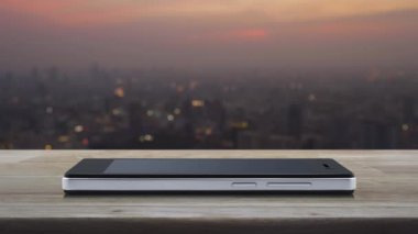 Hediye kutusu mutlu yıllar 2024 modern akıllı cep telefonu ekranında ahşap masa üzerinde düz simge sıcak gün batımında bulanık şehir manzarası üzerinde iş yeni yılı mutlu yıllar 2024 dükkan online konsepti