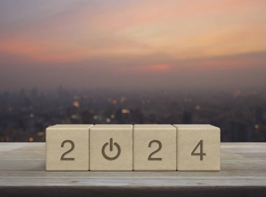 2024 ahşap küpler üzerine ahşap masa üzerine yeni iş simgesi kurun sıcak gün batımında şehir manzarası bulanıklığı, mutlu yıllar 2024 başarı konsepti