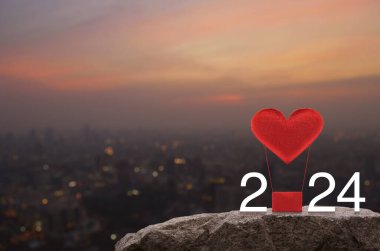 Kırmızı Kumaş Kalp, 2024 beyaz yazılı balonu sever. Sıcak gün batımında Rock Dağları 'nda. Mutlu yıllar ve Sevgililer Günü 2024 konsepti.