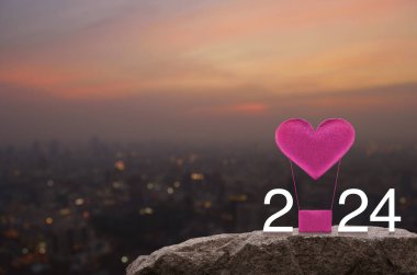 Pembe kumaşlı kalp, 2024 beyaz metinli hava balonunu sever. Sıcak gün batımında Rock Dağları 'nda. Mutlu yıllar ve Sevgililer Günü 2024 konsepti.