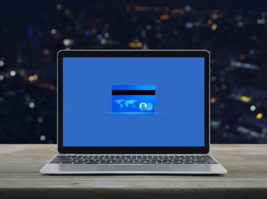 Modern dizüstü bilgisayar ekranındaki kredi kartı ahşap masa üzerindeki bulanık gece lambası ofis kulesi ve gökdelen, Çevrimiçi e-ödeme konsepti NASA tarafından desteklenen bu görüntünün elemanları.