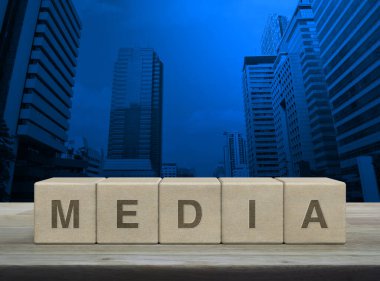 Tahta blok küplere basılı medya mektubu modern ofis kulesi ve gökdelen üzerinde ahşap masa, iş iletişimi konsepti