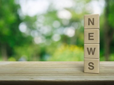 Ahşap küpler üzerindeki NEWS mektubu parktaki bulanık yeşil ağacın üzerindeki ahşap masa, iş iletişimi konsepti