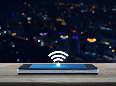 Wi-fi düğme düz simge modern akıllı cep telefonu ekranı ahşap masa üzerinde bulanık gece lambası şehir kulesi ve gökdelen, teknoloji ve internet konsepti
