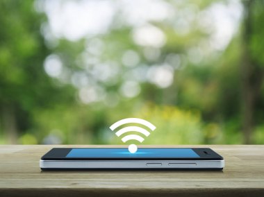 Wi-fi düğme düz simge modern akıllı cep telefonu ekranı ahşap masa üzerinde bulanık yeşil ağaç park, teknoloji ve internet konsepti