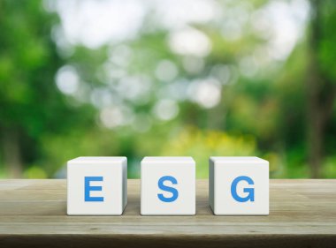 Beyaz blok küplerine ESG kısaltması, parktaki bulanık yeşil ağacın üzerindeki ahşap masa, Çevresel Sosyal Kurumsal Yönetim kavramı