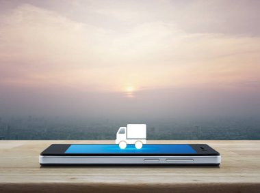 Kamyon teslimatı düz simgesi modern akıllı cep telefonu ekranında ahşap masa üzerinde ve günbatımında gökdelen, klasik tarz, iş ulaşımı çevrimiçi servis konsepti