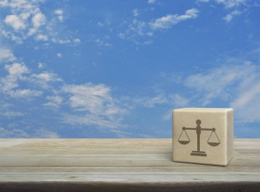 Ahşap blok küpün üzerindeki kanun simgesi mavi gökyüzü üzerinde beyaz bulutlu, iş hukuku hizmeti konsepti