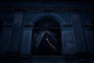 Ölüm meleği, eski hasarlı pencerede, duvarları, kiliseleri, kuşları, ölü ağaçları ve ürkütücü bulutlu gökyüzünü gösteren bir sessizlik işareti gösteriyor.