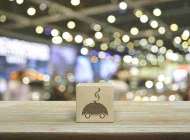 Ahşap kübün üzerindeki restoran ikonu bulanık ışık ve alışveriş merkezinin gölgesi üzerine kurulmuş ahşap masa, iş yemeği teslimatı konsepti