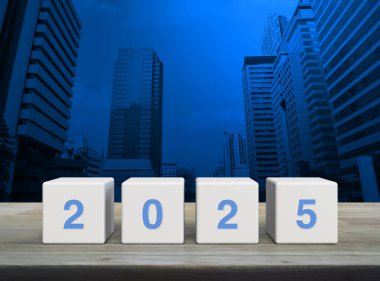 Modern ofis kulesi ve gökdelen üzerindeki ahşap masa üzerinde beyaz blok küpleri üzerinde 2025 mektup, Mutlu yıllar 2025 kapak konsepti