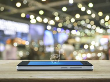 Modern akıllı cep telefonu ekranındaki e-öğrenme simgesi bulanık ışık ve alışveriş merkezinin gölgesi üzerindeki ahşap masa, iş dünyası konsepti