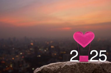 Pembe kumaşlı kalp, 2025 beyaz metinli hava balonuna bayılıyor. Sıcak gün batımında Rock Dağları 'nda. Mutlu yıllar ve Sevgililer Günü 2025 konsepti.