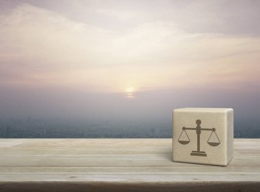 Kanun simgesi ahşap blok küp üzerinde ahşap masa üzerinde ve günbatımında gökdelen, klasik tarzı, iş hukuku konsepti