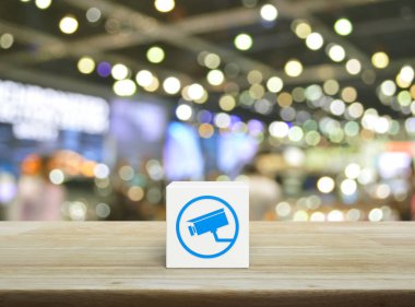 Kapalı devre kamera yassı simgesi beyaz blok küp üzerinde ahşap masa üzerinde bulanık ışık ve alışveriş merkezinin gölgesi, Teknoloji güvenliği ve güvenlik online konsepti