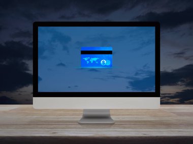 Günbatımı gökyüzü üzerindeki ahşap masa üzerinde modern bilgisayar monitörü üzerindeki kredi kartı, Çevrimiçi e-ödeme konsepti, NASA tarafından desteklenen bu görüntünün unsurları