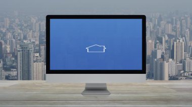 Masaüstü modern bilgisayar monitöründeki ev simgesiyle çekiç ve anahtar ofis binasının üzerindeki ahşap masa üzerinde ve şehirdeki gökdelen, İş Ev Servisi online konsepti