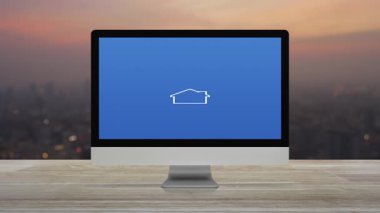 Masaüstü modern bilgisayar monitörü ekranında ev simgesiyle çekiç ve ingiliz anahtarı sıcak gün batımında şehir manzarasının bulanıklığı üzerinde ahşap masa, iş yeri internet hizmeti kavramı