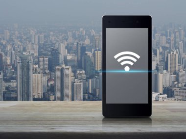 Wi-fi bağlantısı düz simge modern akıllı cep telefonu ekranı ahşap masa üzerinde şehir kulesi ve gökdelen, teknoloji ve internet kavramı