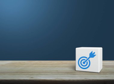 Dart düz ikonlu hedef beyaz blok küp üzerinde ahşap masa üzerinde açık mavi duvar üzerinde, iş başarısı konsepti