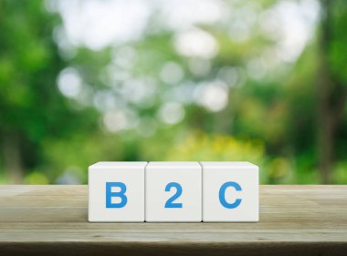 Beyaz blok küplerinde B2C kısaltması parktaki bulanık yeşil ağacın üzerindeki ahşap masa üzerinde müşteri pazarlama ve strateji kavramına