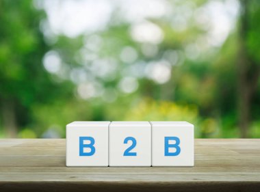 B2B kısaltması beyaz blok küpleri üzerinde ahşap masa üzerinde park bulanık yeşil ağaç üzerinde, işletmeden iş pazarlama ve strateji kavramı