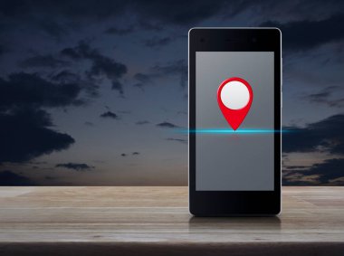 Günbatımı gökyüzü üzerinde ahşap masa üzerinde modern akıllı cep telefonu ekranı üzerinde harita pin düğmesi, harita işaretleyici navigasyon kavramı