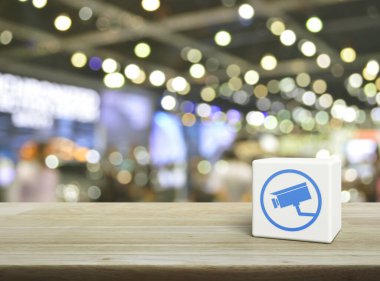 Kapalı devre kamera yassı simgesi beyaz blok küp üzerinde ahşap masa üzerinde bulanık ışık ve alışveriş merkezinin gölgesi, Teknoloji güvenliği ve güvenlik online konsepti