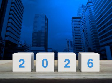 2026 letter on white block cubes on wooden table over modern office city tower and skyscraper, Happy new year 2026 cover concept