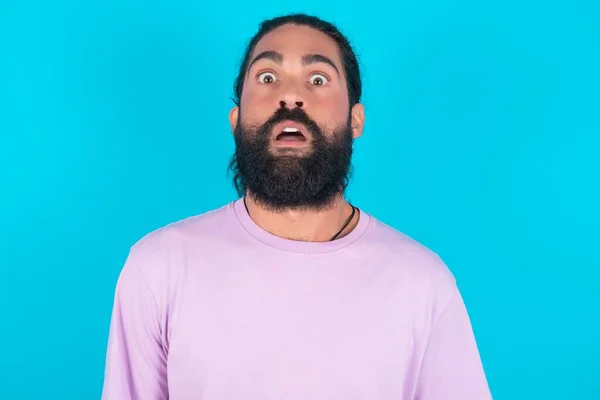 Homem Caucasiano Chocado Com Barba Vestindo Camiseta Violeta Sobre Azul — Fotografia de Stock
