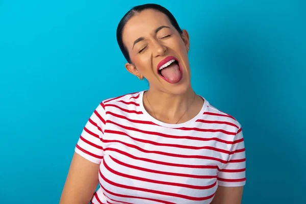 ハッピーで面白い顔のストライプTシャツを着て舌を示す女性 — ストック写真