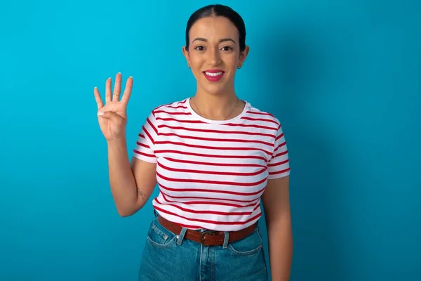 ストライプTシャツを着た女性は自信と幸せを笑いながら指ナンバー4を指さして指を指さす — ストック写真