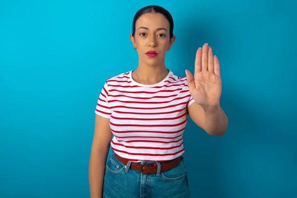 woman doing stop gesture with palm of the hand. Warning expression with negative and serious gesture on the face.