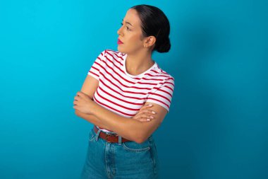 Kolları çapraz çizgili tişört giyen üzgün bir kadın görüntüsü. Kötü haberleri dinledikten sonra hayal kırıklığına uğramış bir ifadeyle bakıyorum..