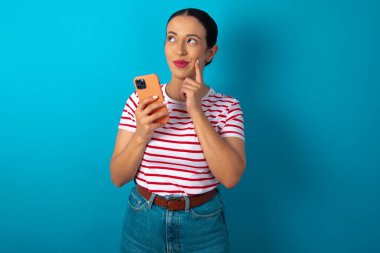 Çizgili tişört giyen, cep telefonu kullanan ve el ele tutuşan bir kadın hayal et. Karar almak ve sosyal medya kavramı.