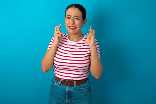Mulher Vestindo Listrado Camiseta Segurando Dedos Cruzados Com Expressão Preocupada — Fotografia de Stock