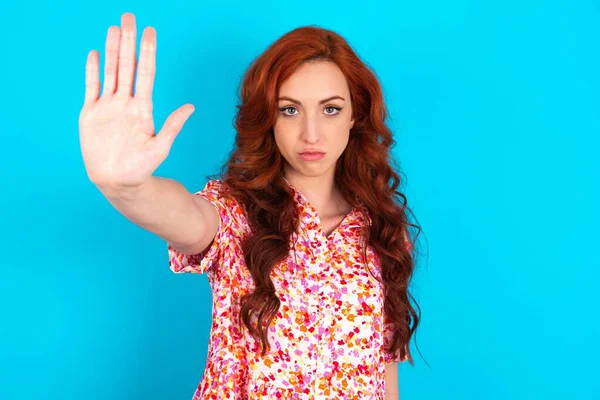 woman doing stop gesture with palm of the hand. Warning expression with negative and serious gesture on the face.