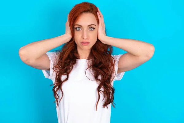 Frustrerad Rödhårig Kvinna Bär Vit Shirt Över Blå Bakgrund Pluggning — Stockfoto