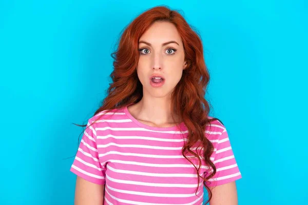 Shocked Redhead Woman Wearing Pink Striped Shirt Blue Background Stares — Stock Photo, Image