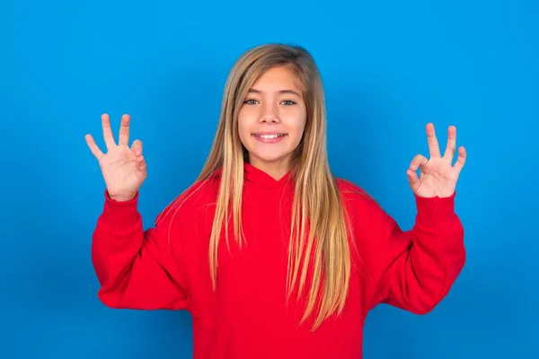 Froh Kaukasisches Teenie Mädchen Trägt Rotes Sweatshirt Über Blauem Hintergrund — Stockfoto