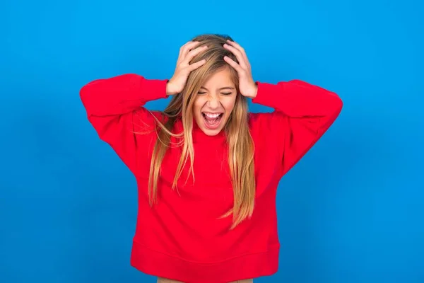 Chocado Caucasiano Teen Menina Vestindo Vermelho Sweatshirt Sobre Azul Fundo — Fotografia de Stock