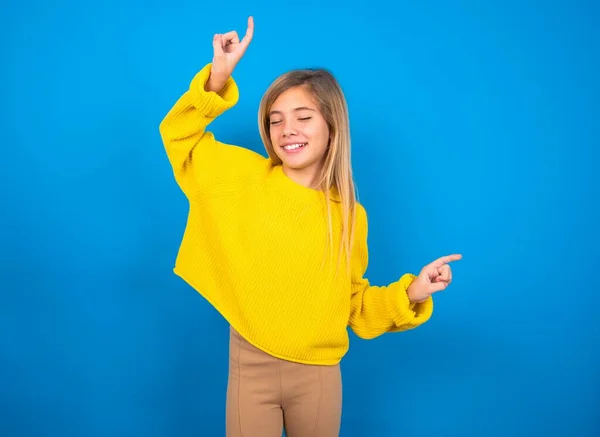 照片上乐观的高加索少女穿着黄色毛衣在蓝色工作室的背景有乐趣 跳舞无忧无虑的穿着完美的心情使动作 花些时间在迪斯科舞会上 — 图库照片