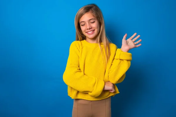 在蓝色工作室背景下穿着黄色毛衣的成功的高加索少女高兴地举起手掌 在朋友们的欢愉中闭上眼睛 — 图库照片