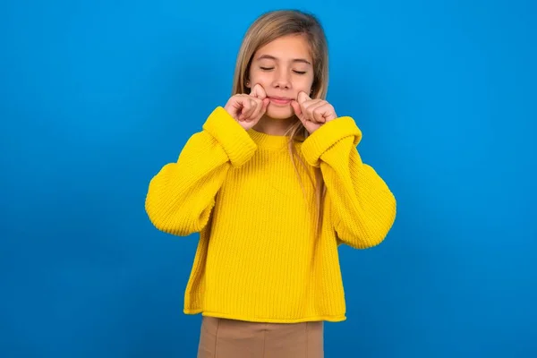 Pleased Beautiful Caucasian Teen Girl Wearing Yellow Sweater Blue Studio — Stock Photo, Image
