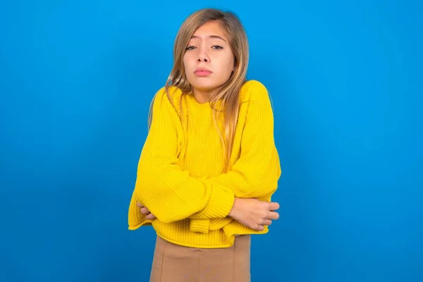 青い背景に顔に悲しくショックな表情と冬の寒さのために揺れて凍っている黄色いセーターを着て美しい白人十代の少女 — ストック写真