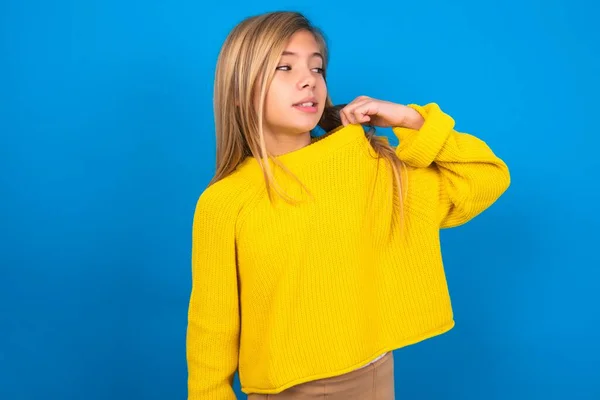 青いスタジオの背景に黄色のセーターを着用している白人十代の少女は ストレス イライラ シャツの首を引っ張り 問題にイライラしている — ストック写真