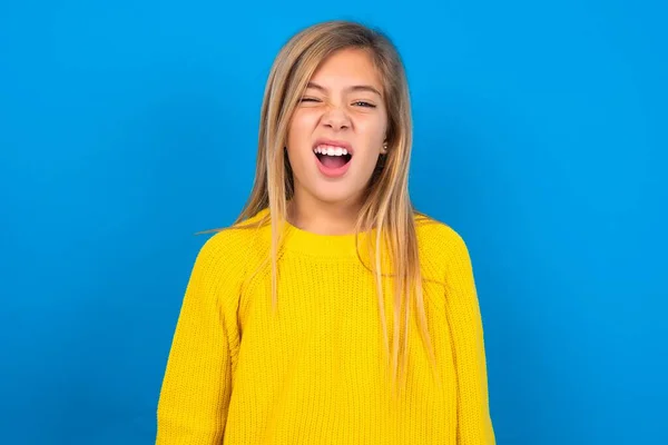 青いスタジオの背景に黄色いセーターを着ている白人の十代の少女は 口を開いたスタンドを立てます 毎日の朝のルーチン — ストック写真