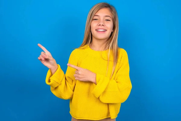 Kaukasisch Tiener Meisje Dragen Gele Trui Blauwe Muur Wijst Kopieerruimte — Stockfoto